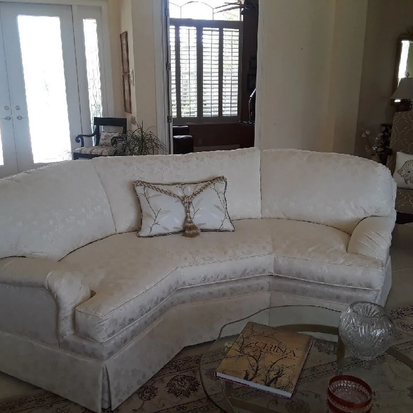 A curved upholstered sofa with custom pillows in a bright living room